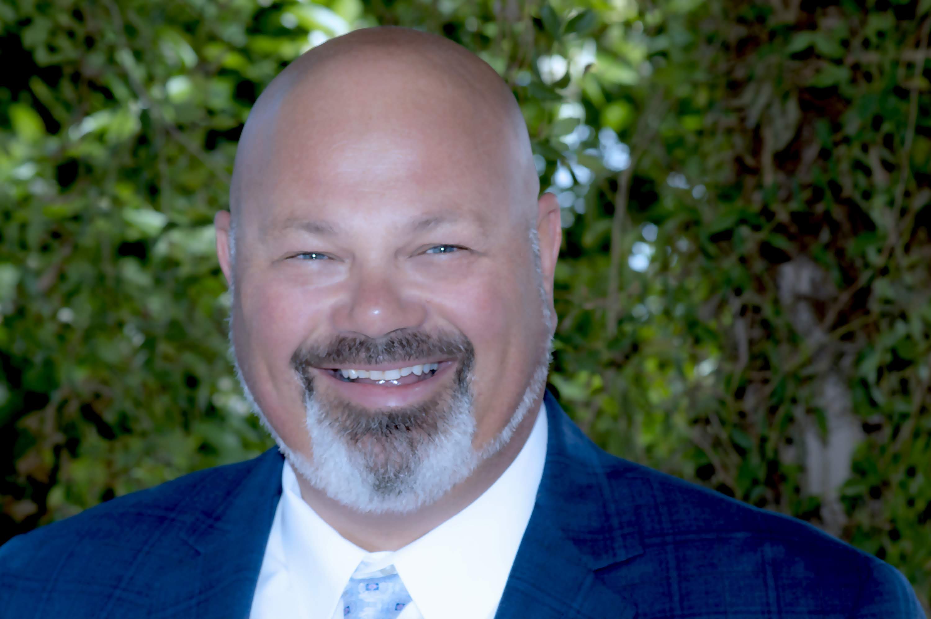 Professional headshot of a smiling man outdoors