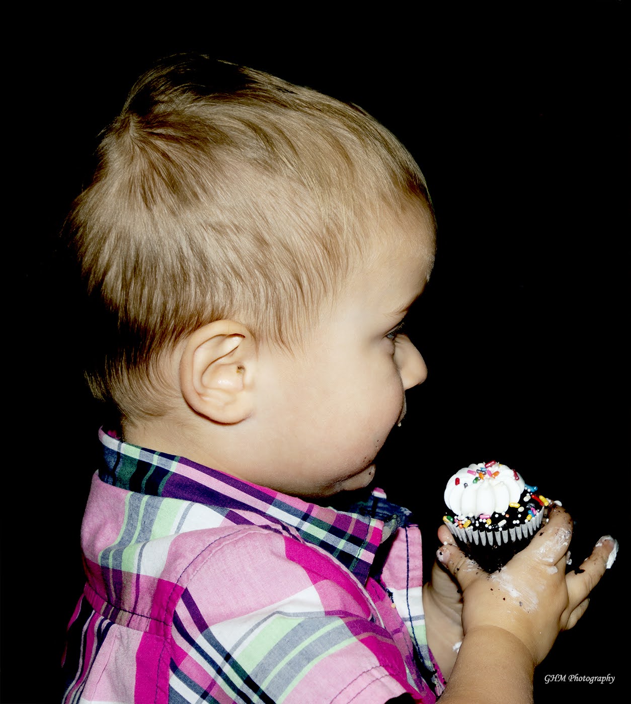 A young child carefully holding a birthday cupcake